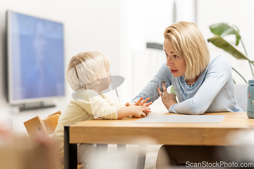 Image of Caring young Caucasian mother and small son drawing painting in notebook at home together. Loving mom or nanny having fun learning and playing with her little 1,5 year old infant baby boy child.