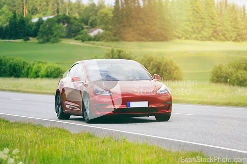 Image of Red Tesla Model 3 Electric Car on Sunny Road