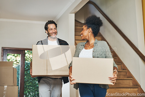 Image of Couple homeowners moving in, carrying boxes and unpacking in new purchased home as real estate investors. Smiling, happy and cheerful interracial man and woman, first time buyers and property owners