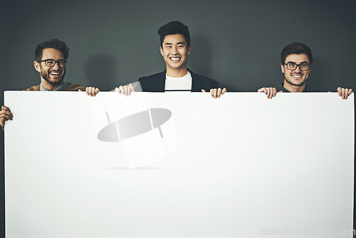 Image of A group of young, smiling and professional business men holding a white sign copyspace portrait. A team of male designers standing together with a blank billboard for advertising or marketing