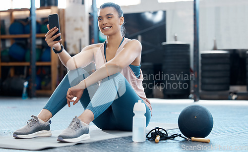 Image of Woman taking selfie with phone after workout at the gym, reading social media post and relax after cardio fitness exercise at club. Athlete girl on mobile app for sports while training on floor