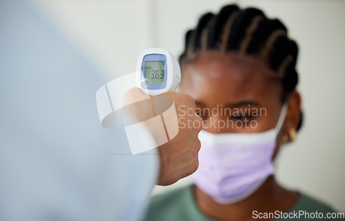 Image of Covid, healthcare and woman patient getting thermometer check with a compliance officer during consultation or appointment. Health, hygiene regulations and wellness with a female wearing a face mask