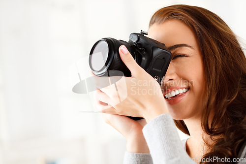 Image of Happy woman photographer doing a photoshoot with a camera in a studio with copy space. Art, creative and young lady with a photography career taking a picture for a artistic work project.