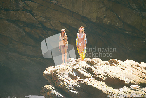 Image of Summer, bikini and holiday, women on a cliff in the sun, ready to jump into the water. Travel, beauty and adventure, young girls relax on vacation in the sun with rock face or cave in the background.