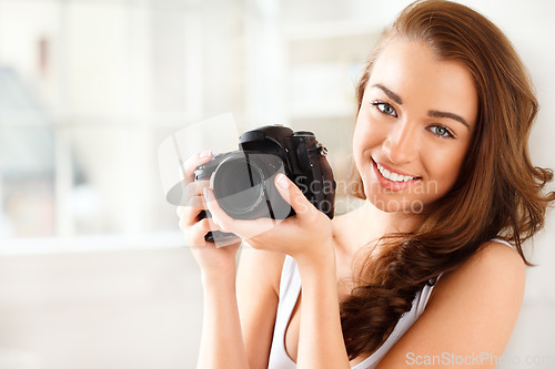 Image of Photographer, digital camera and photography with a woman taking a photograph or picture inside. Portrait of a young female with a smile holding photo gear for a beauty shoot with a happy model