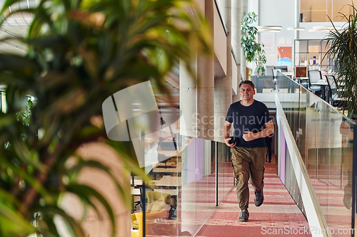 Image of In the hustle and bustle of a modern startup office, a determined businessman sprints towards his office, embodying the fast-paced, ambitious spirit of contemporary entrepreneurship