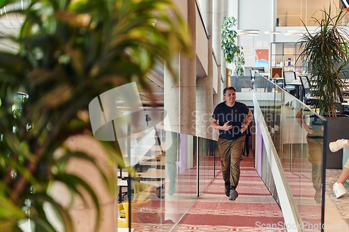 Image of In the hustle and bustle of a modern startup office, a determined businessman sprints towards his office, embodying the fast-paced, ambitious spirit of contemporary entrepreneurship