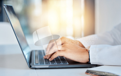 Image of Doctor hands typing on a laptop doing medicine research at a hospital table and reading email online at work. Healthcare expert or medical professional using keyboard and consulting via the internet