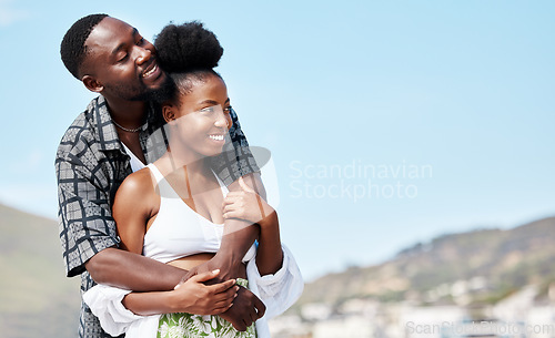 Image of Young, love and black couple on beach hug while bonding together in blue sky seaside scenery. Happy African American people in joyful relationship embrace each other on peaceful outdoor date.