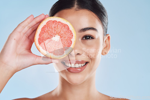 Image of Portrait of woman with happy face and grapefruit in blue studio background. Her skincare and wellness beauty routine keeps her body fresh or healthy dental hygiene and clean smile or white teeth