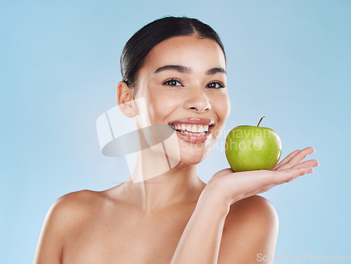 Image of Wellness, health and beauty with woman and an apple for nutrition, detox and green diet against a blue background. Nutritionist, smile and fruit with happy female eating healthy for natural lifestyle