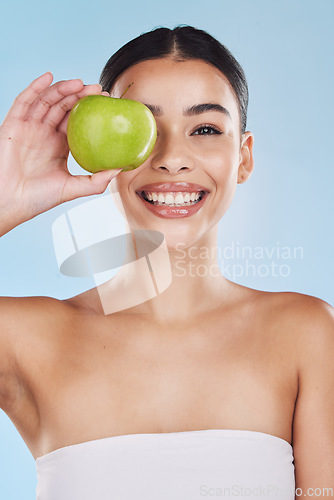 Image of Portrait, health and beauty with woman with an apple for vitamins, minerals or nutrients. Healthy diet, lifestyle and skincare nutrition of girl from Brazil with fruit on her eye and a smile.