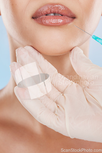 Image of Needle, surgery and lips with a woman getting an injection in her mouth for beauty, skincare and medicine in studio on a blue background. Filler, product and cosmetics with a young female model inside