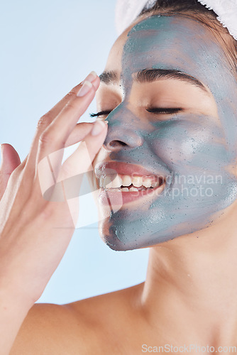 Image of Charcoal face mask for beauty skincare, natural product for healthy skin and clean cosmetic wellness for body against blue mockup studio background. Happy, smile and healthcare on woman model