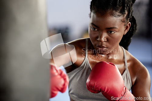 Image of Woman, boxing and gym training workout for strong and motivated athlete fighter fitness. Hand coordination, focus and concentration for punching bag strike exercise in sports facility.