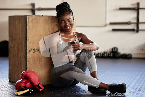 Image of Phone, fitness and app with a black woman boxer tracking her workout, exercise and progress with a mobile application in a gym. Health, wellness and sport with a female athlete typing a text message
