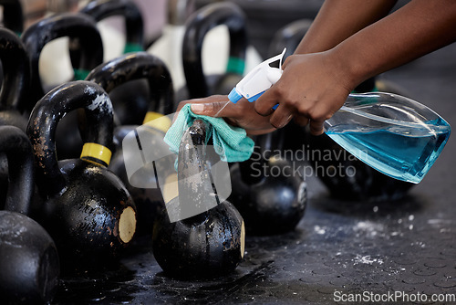 Image of Gym cleaning hand spray bottle to sanitize dumbbell weights in gym. Woman cleaning equipment in hygiene routine to protect and prevent covid or corona through exercise with chemical liquid detergent