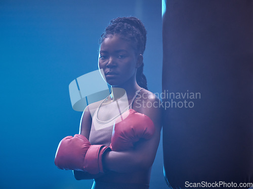 Image of Fitness, boxer and gym of a black woman in sports professional for strength and motivation. Portrait of a African female in serious and confident boxing at health club standing by punching bag