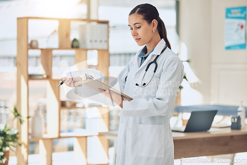 Image of Insurance, healthcare and medicine with a doctor reading paperwork in a clipboard in her office in the hospital. Medical, review and wellness with a female professional in the health industry