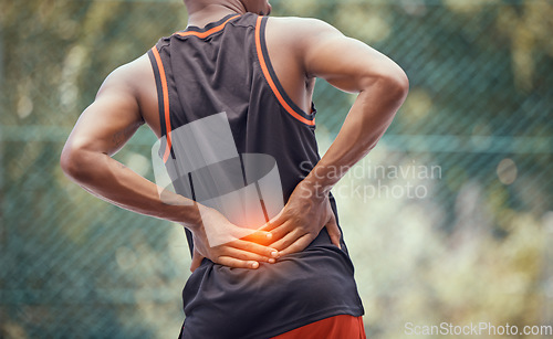 Image of Athletic, fit man with lower back pain, outdoors hold and massages tired and strain muscles or spinal injury. Muscular black man with cramps, inflammation or burning and sore muscle seeking relief.