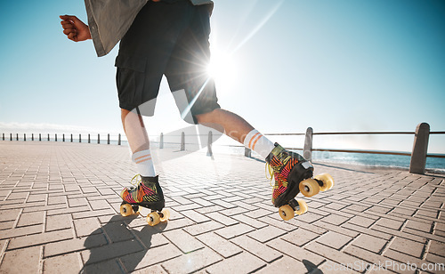 Image of Person roller skating, sport and fitness on a sidewalk, sea or ocean shore. Sun flare, exercise and sports with roller skate cardio workout, training for wellness, strength and health on promenade.