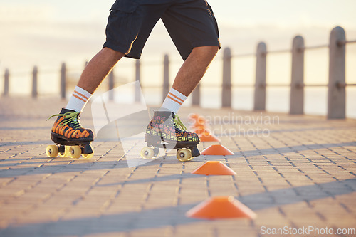 Image of Roller skates, sport and feet with a man riding around cones for training, fitness and exercise on the promenade by the beach. Male athlete roller skating outside for sports, health and recreation