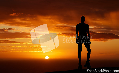 Image of Sunset, silhouette and woman admiring the horizon view and watching the sun and orange or red sky while enjoying freedom, relax and mindfulness. Travel, scenery and beauty of nature by the sea