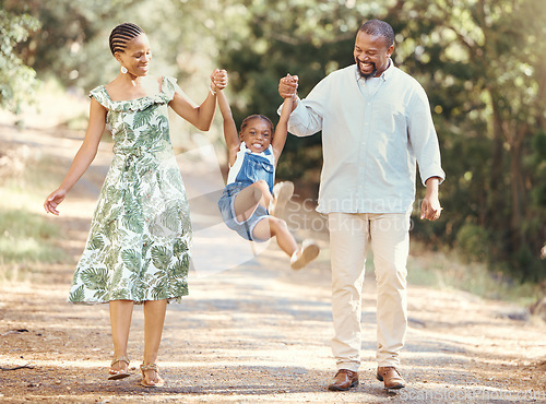 Image of Happy parents swing girl at their hands in the forest during a walk in nature. Cheerful kid having fun while bonding with mother and father on family summer vacation or outing together in the woods