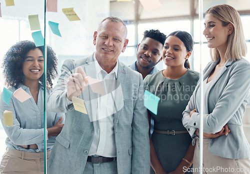 Image of Training, coaching or learning with a manager, leader or CEO and his team working with sticky notes on a glass wall during a meeting. Teamwork, collaboration or planning with a business man and staff