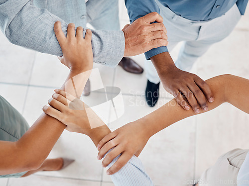 Image of Hands, teamwork and collaboration with a team of business people holding arms in a huddle or pentagon from above. Trust, support or motivation of group at work or office in solidarity, unity or union