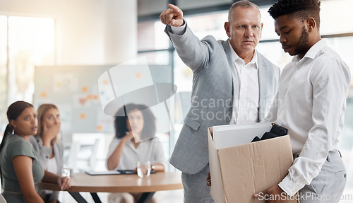 Image of Black man, sad and fired by boss in a meeting holding a box in disappointment at the office. Manager or company leader pointing to the exit and firing employee in front of colleagues at the workplace