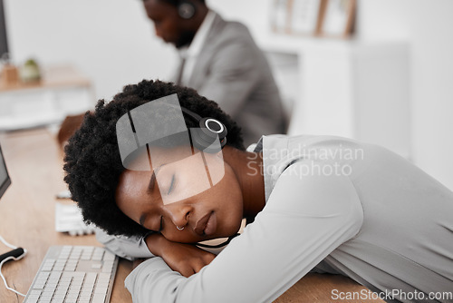 Image of Call center, burnout and sleep of a woman employee resting on a desk at the office. Exhausted black female telemarketing agent or consultant in customer support or service sleeping on the job at work