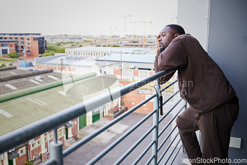 Image of Sad, burnout and depression man with health, anxiety and thinking of mental health on balcony in house. Depressed, frustrated and tired African man with fail, stress or headache pain from work report