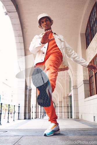 Image of Fashion, model and gen z man from Spain with neon, trendy and luxury brand clothes. Clothing brand and leg kick pose of a hipster Spanish person with sports shoes posing by a building outdoors