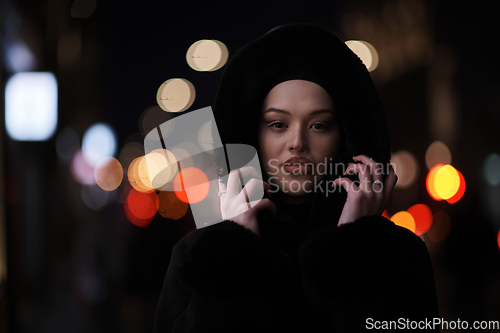 Image of Muslim woman walking on urban city street on a cold winter night wearing hijab