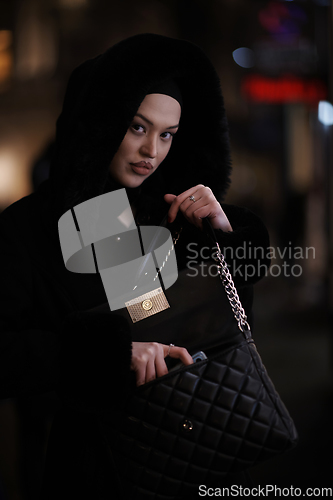 Image of Muslim woman walking on urban city street on a cold winter night wearing hijab