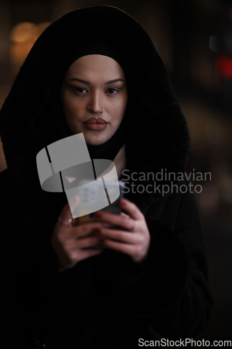 Image of Muslim woman walking on urban city street on a cold winter night wearing hijab