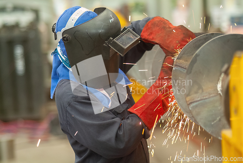 Image of Worker using an angle grinder, making a screw conveyor