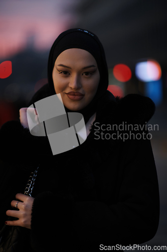 Image of Muslim woman walking on an urban city street on a cold winter night wearing hijab