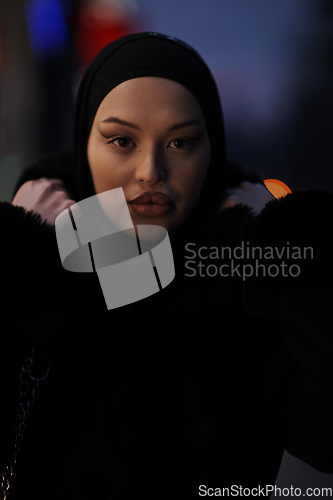 Image of Muslim woman walking on an urban city street on a cold winter night wearing hijab