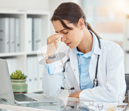 Image of Stress, depression and tired female doctor suffering from a headache or mental health while sitting in an office with laptop. Frustrated, upset and overworked healthcare or medical worker in hospital