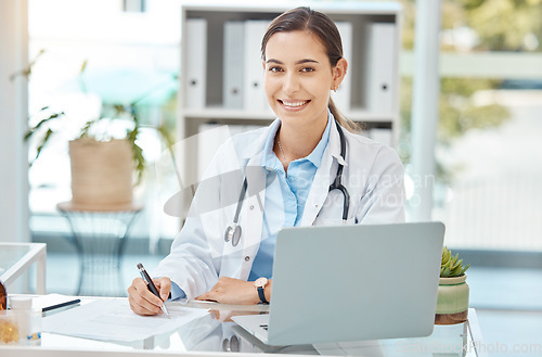 Image of Healthcare, medicine and a doctor writing on insurance document or patient file. Happy woman working in medical field, at desk with laptop consulting online and filling in a script at hospital office