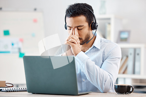 Image of Stress, headache and depression of call center agent feeling overwhelmed, upset and frustrated while wearing headset and using laptop at desk. Male crm, telemarketing and customer support operator