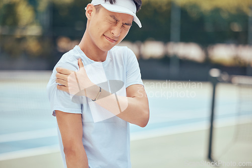 Image of Tennis arm, man and pain on the court while playing competitive and intense game workout outside. Inflammation, accident and injury at sports training practice with asian athlete holding muscle.
