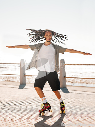 Image of Training, sports and skate with a man roller skating on the promenade by the beach with the sea in the background. Fitness, fun and freedom with a young male on roller skates outside in summer