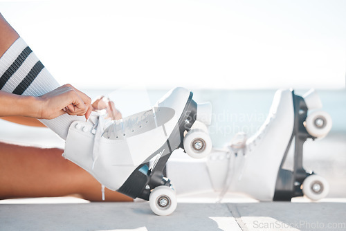 Image of Closeup of roller skate shoes on the floor outdoor on the promenade at the beach during spring. Person putting on skating boots to do a fun sports activity for exercise in nature at the ocean.