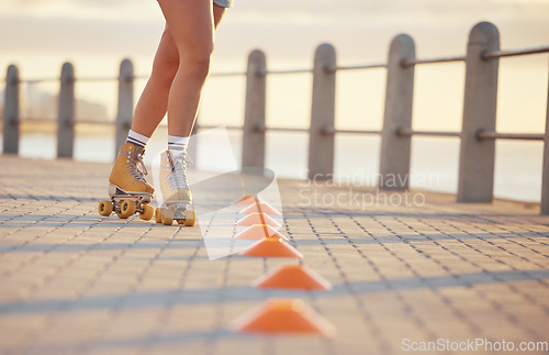Image of Woman roller skating with fitness cones outdoor on the promenade at the beach during summer. Girl practicing her skating skill while training for a sports activity in nature at the ocean.