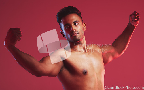 Image of Bodybuilder, muscle and fitness with a nude man model posing shirtless in studio with a red background. Naked, strong weightlifter with a healthy male flexing arms inside for health and wellness