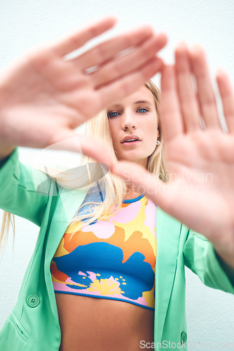 Image of Beautiful model, a triangle sign with fashion hands looking though it in bright, colorful clothes. Portrait of a young beautiful woman with artistic, trendy and funky style standing outdoors.