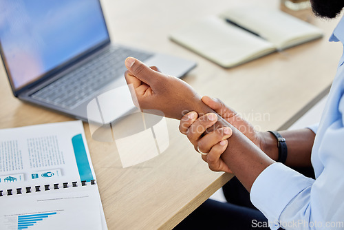 Image of Wrist pain, business man and muscle injury while sitting at desk and working as a data analyst. Closeup hand of a black male entrepreneur suffering from carpal tunnel syndrome or arthritis in office